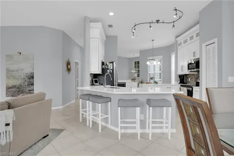 a kitchen with stainless steel appliances kitchen island granite countertop a dining table chairs and sink