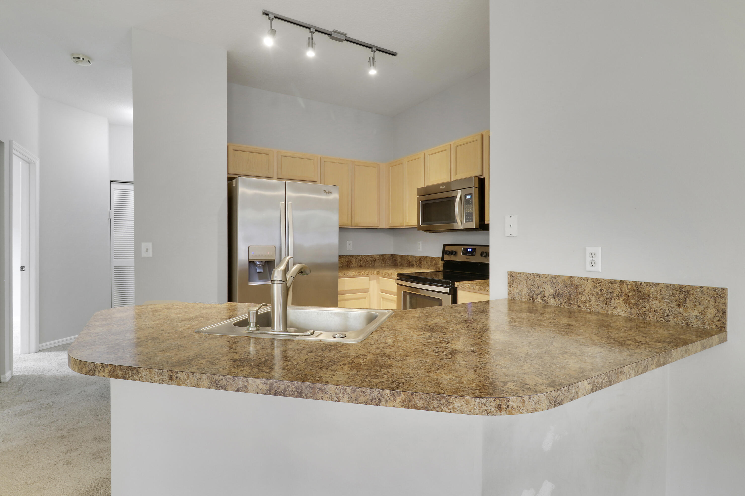 104 Lighthouse Circle, Unit H2 Tequesta, FL 33469 - Photo 11 of 45 a kitchen with kitchen island a sink stainless steel appliances and a counter top space