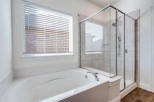 a bathroom with a bathtub a shower and a window