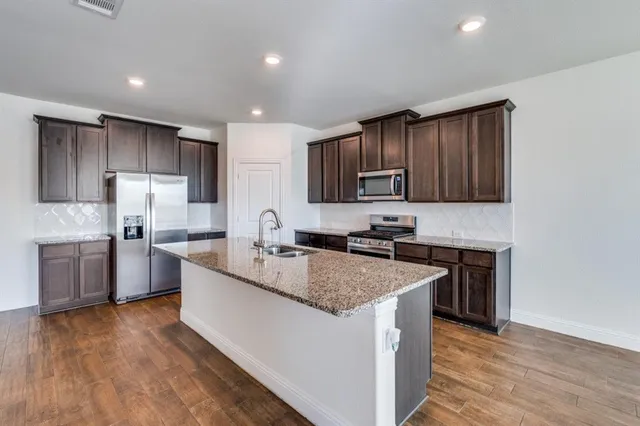 a kitchen with stainless steel appliances granite countertop a sink stove microwave and refrigerator