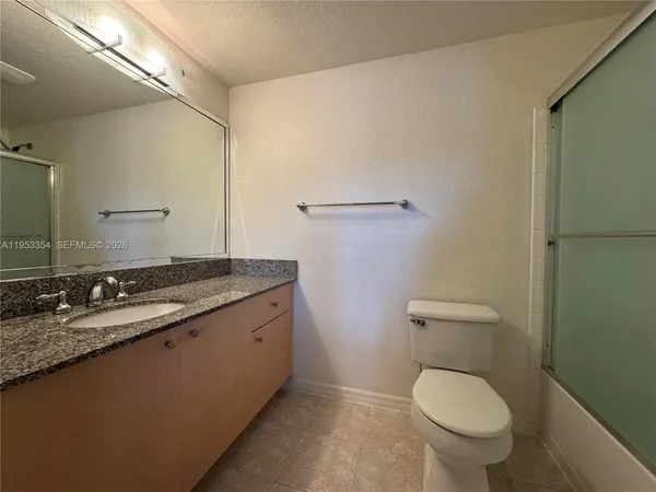 a bathroom with a granite countertop toilet and a sink