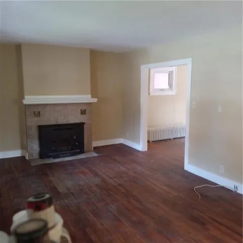 an empty room with wooden floor a fireplace and windows