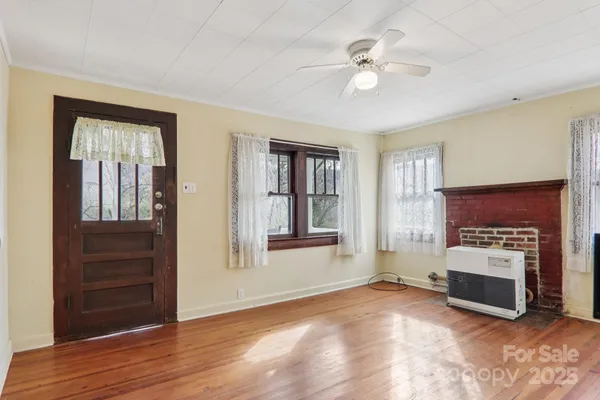 a view of a livingroom with a fireplace a ceiling fan and windows
