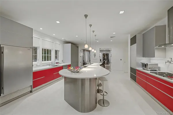 a room with stainless steel appliances kitchen island granite countertop a refrigerator and a sink