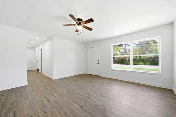 a view of an empty room with wooden floor and a window