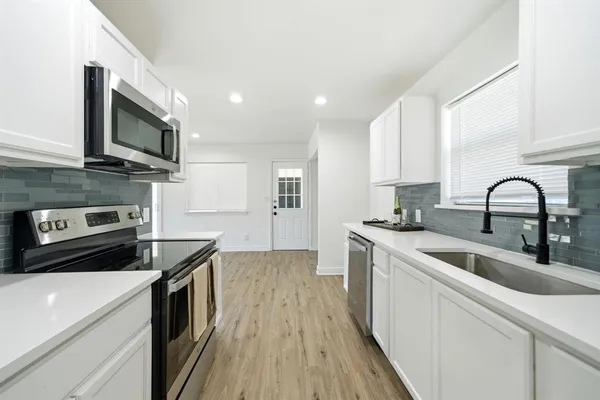 a kitchen with stainless steel appliances granite countertop a stove a sink and a microwave