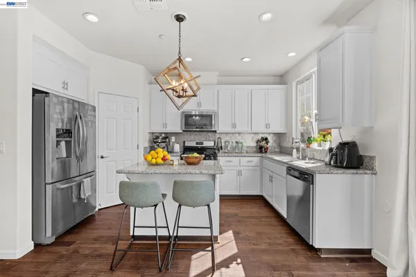 a kitchen with stainless steel appliances granite countertop a sink a stove a refrigerator cabinets and chairs