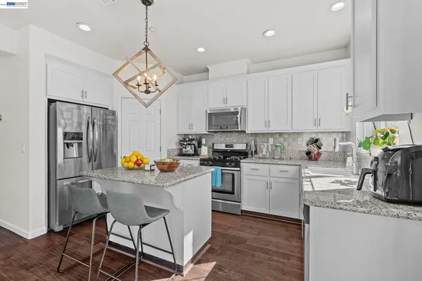 a kitchen with granite countertop stainless steel appliances a sink a stove a refrigerator cabinets and dining table