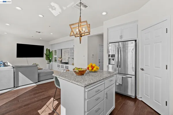 a kitchen with stainless steel appliances granite countertop a refrigerator a sink dishwasher a oven and a dining table with wooden floor