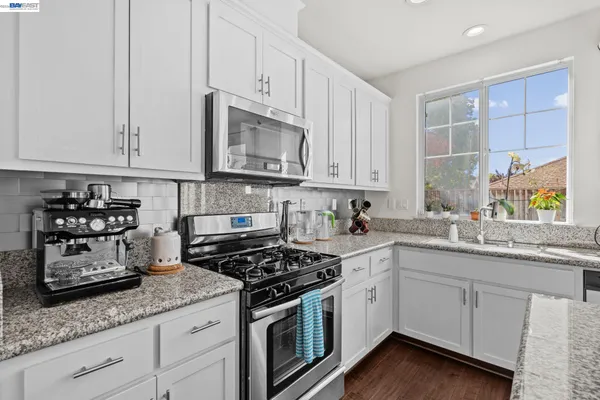 a kitchen with stainless steel appliances granite countertop a sink a stove and cabinets