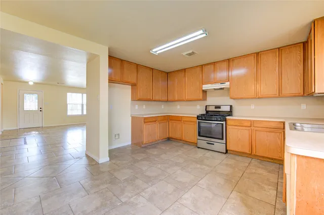 a view of an empty room with a window and a kitchen