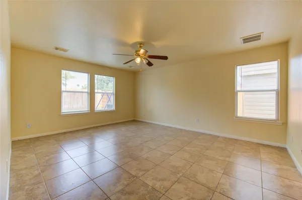 an empty room with windows and chandelier fan