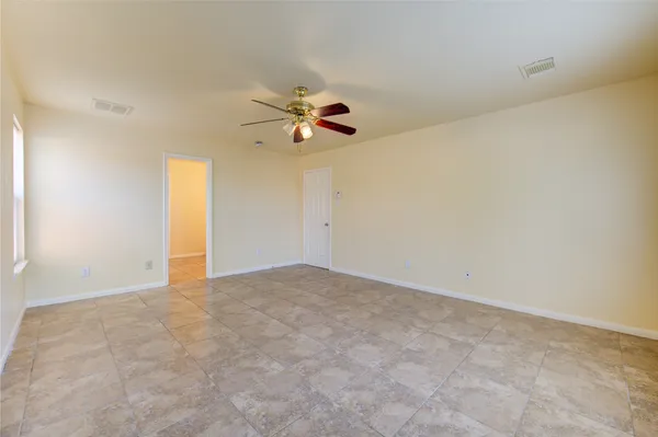 a view of an empty room with a ceiling fan and window