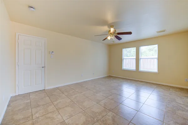 an empty room with windows and chandelier fan