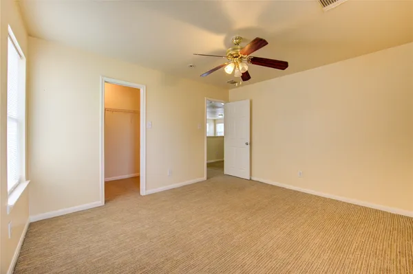 an empty room with windows and fan