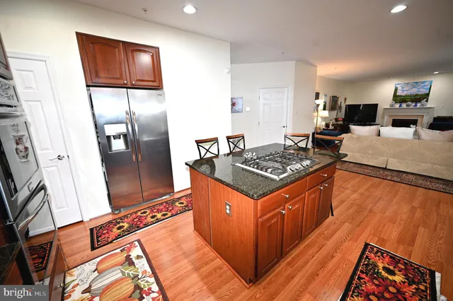 a kitchen with stainless steel appliances kitchen island granite countertop wooden floor a dining table and chairs