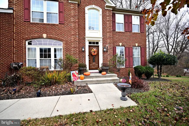 front view of a brick house with a large windows and flower plants