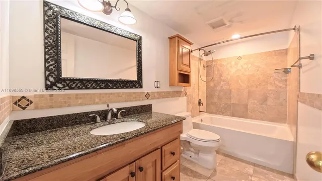 a bathroom with a granite countertop sink mirror toilet and bathtub