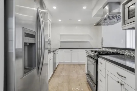 a kitchen with a refrigerator and white cabinets