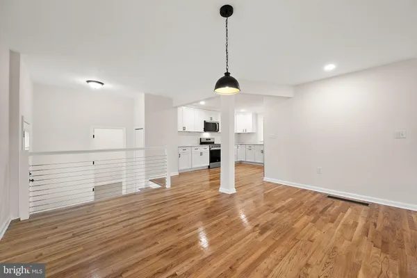 a view of kitchen and empty room with wooden floor