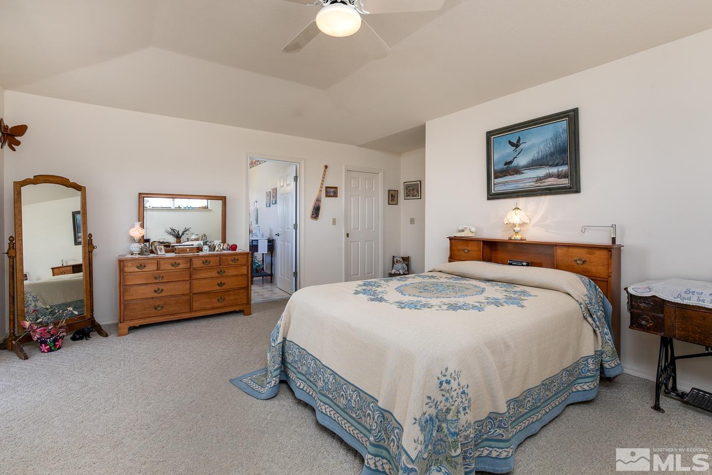 3812 Boyer Road Fallon, NV 89406 - Photo 12 of 40 a spacious bedroom with a bed a couch and a chandelier