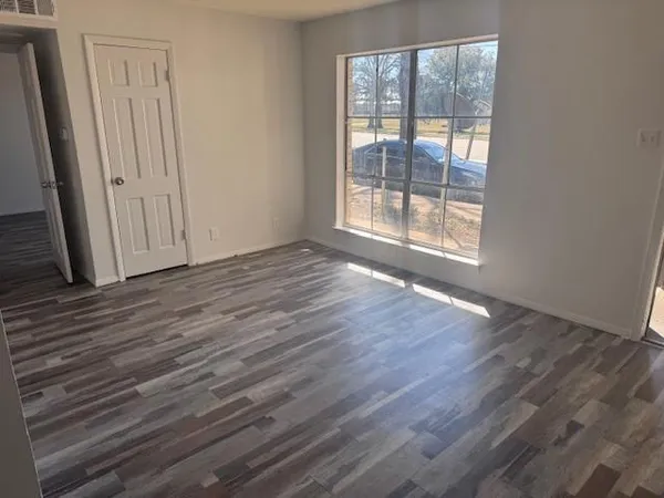 a view of an empty room with wooden floor and a window