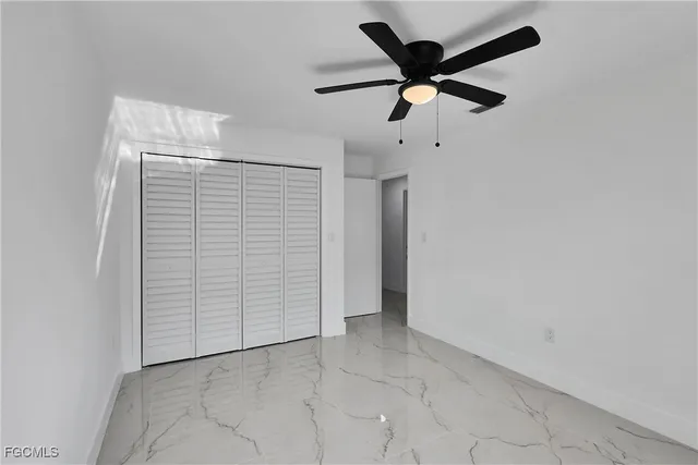 an empty room with closet and ceiling fan