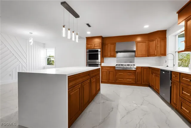 a large kitchen with stainless steel appliances kitchen island granite countertop a sink and cabinets