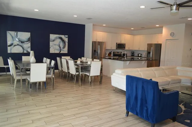 a kitchen with stainless steel appliances kitchen island granite countertop a dining table chairs and a refrigerator