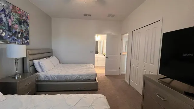 a spacious bedroom with a bed and a flat screen tv