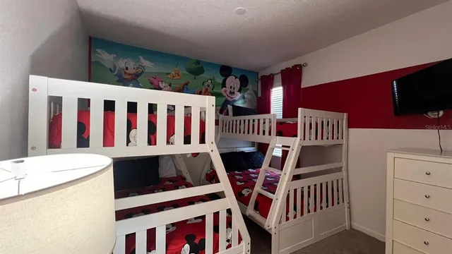 a large bed sitting in a bedroom next to a window and a chandelier