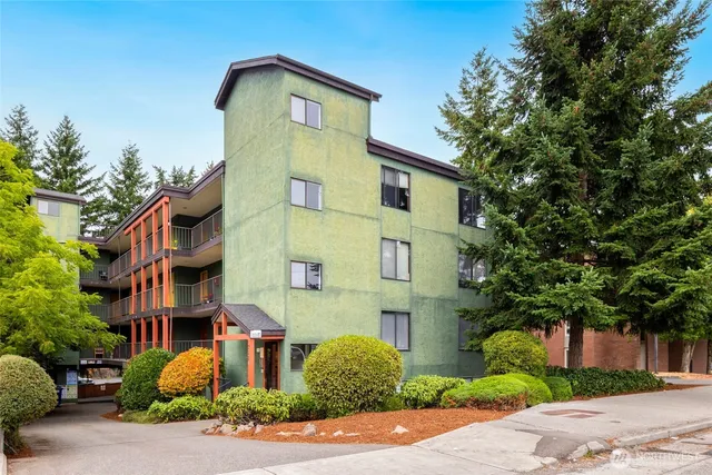 a front view of a multi story residential apartment building with yard and parking space
