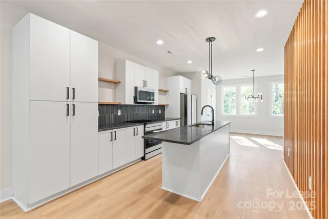 a kitchen with stainless steel appliances granite countertop a refrigerator a sink dishwasher a oven with white cabinets and wooden floor