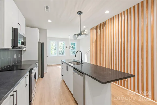 a kitchen with kitchen island granite countertop stainless steel appliances a sink stove and refrigerator