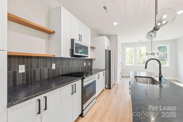 a kitchen with granite countertop a sink and white cabinets
