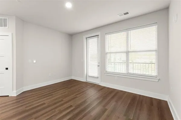 an empty room with wooden floor and windows