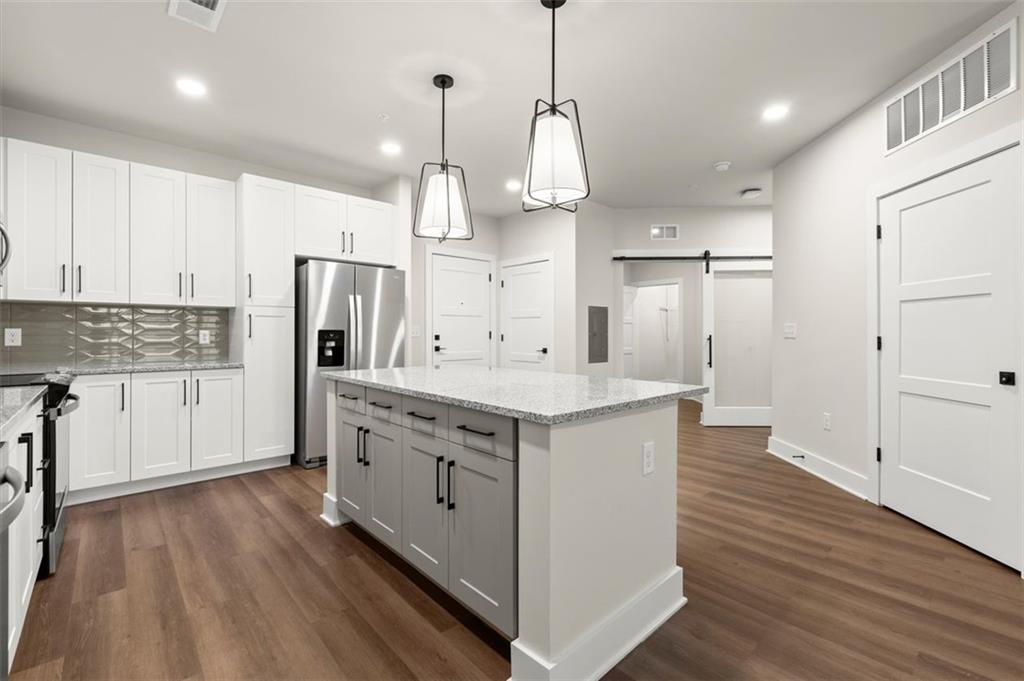 2648 Sandy Plains Road, Unit 137 Marietta, GA 30062 - Photo 4 of 38 a large kitchen with stainless steel appliances kitchen island granite countertop a refrigerator a sink dishwasher a stove and white cabinets with wooden floor