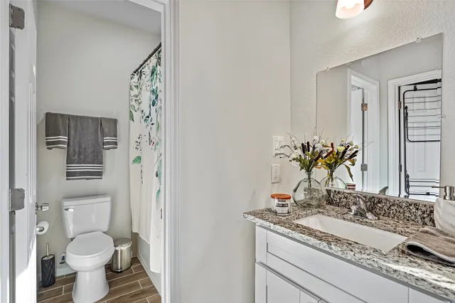 a bathroom with a granite countertop toilet sink and mirror