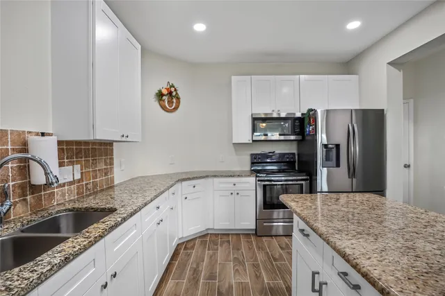 a kitchen with granite countertop a sink stainless steel appliances and counter space