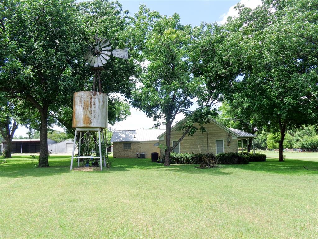 1717 Pipeline Road Cleburne, TX 76033 - Photo 24 of 33 Expansive green lawn featuring mature trees and a rustic windmill with an elevated water tank