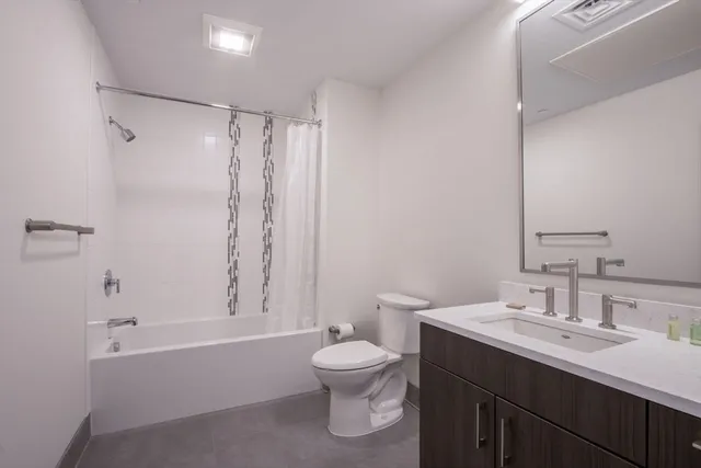 a bathroom with a bathtub shower sink mirror and toilet