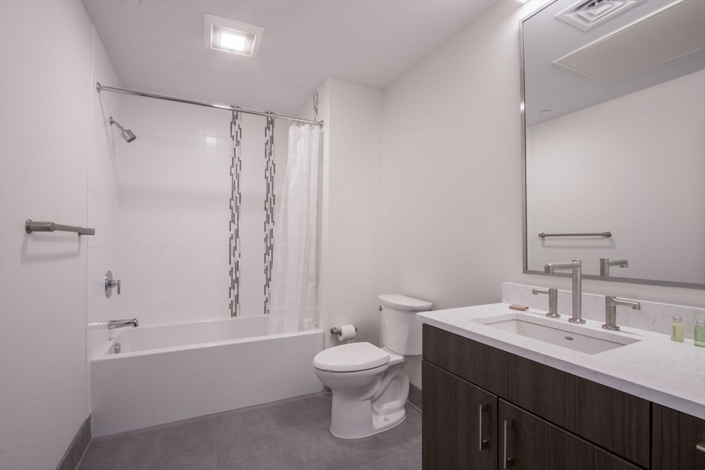 900 Beacon Street, Unit 205 Boston, MA 02215 - Photo 10 of 11 a bathroom with a bathtub shower sink mirror and toilet