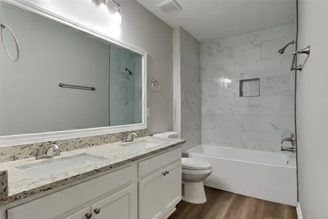 a bathroom with a granite countertop sink a toilet and bathtub
