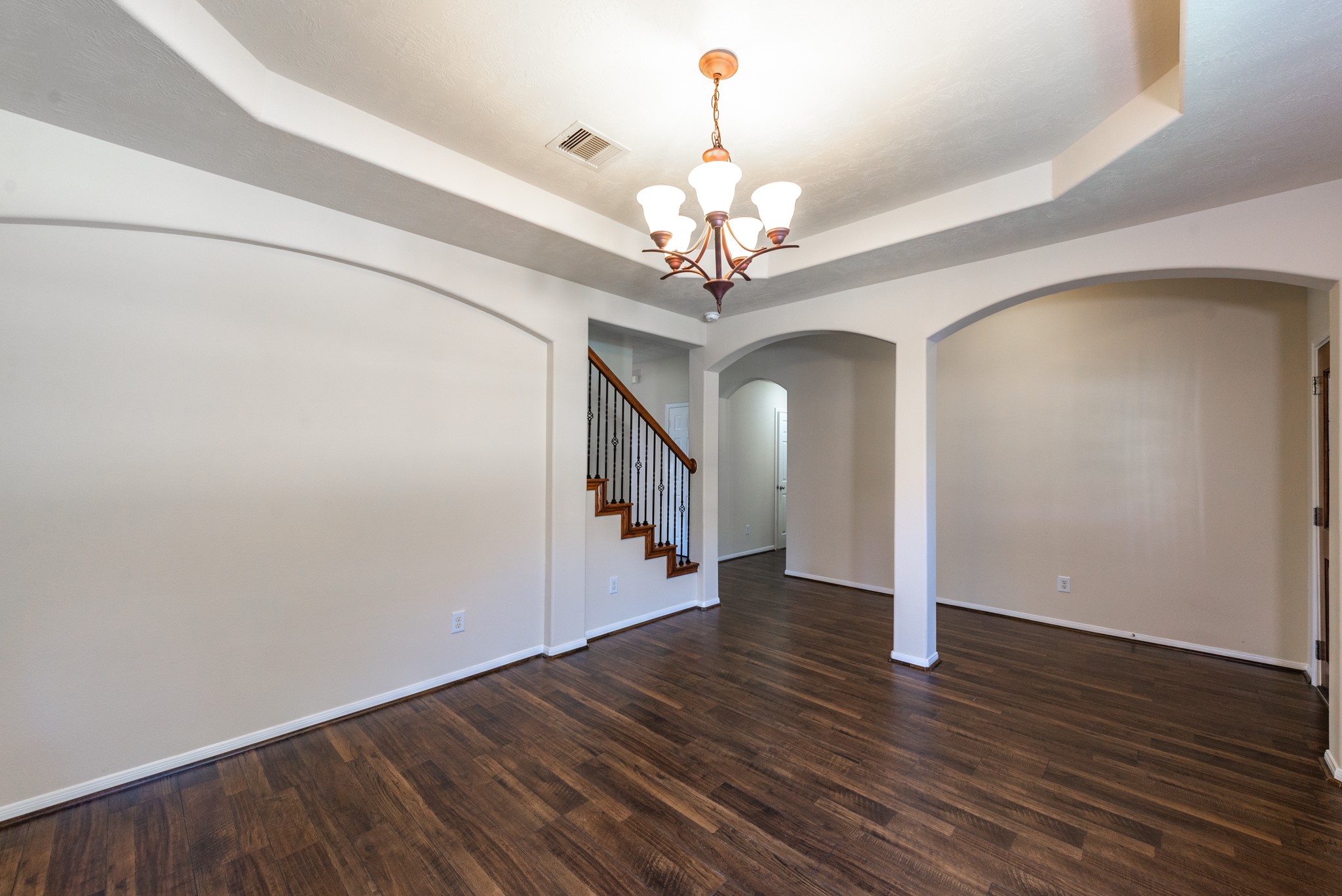 26302 Fox Ridge Lane Katy, TX 77494 - Photo 10 of 35 Elegant room featuring rich hardwood floors, decorative ceiling with a stylish chandelier, and graceful archways leading to a staircase.