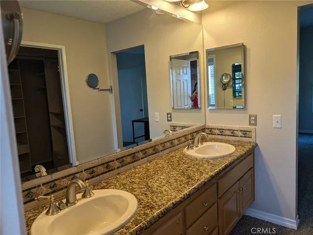 a bathroom with a granite countertop double vanity sink and a mirror