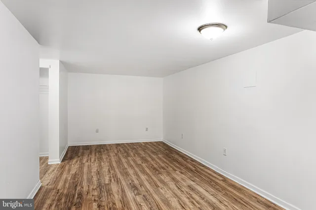 a view of an empty room with wooden floor and a ceiling fan