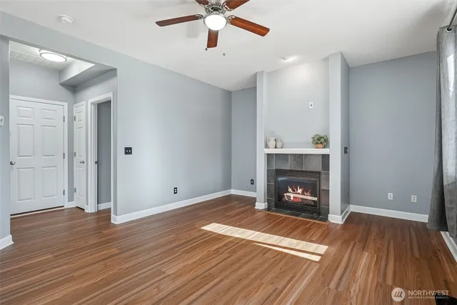 a view of an empty room with wooden floor fireplace and a window