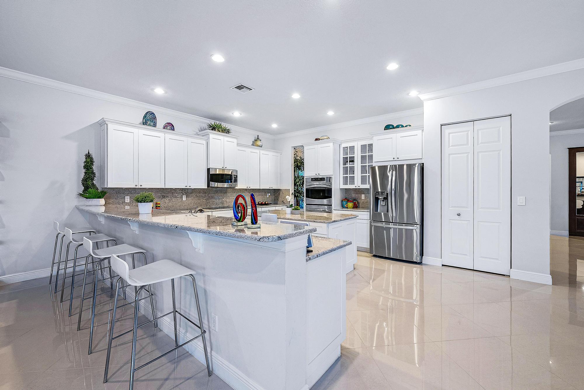 127 Steeple Circle Jupiter, FL 33458 - Photo 9 of 56 a kitchen with stainless steel appliances a refrigerator sink and white cabinets