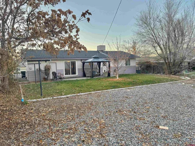 a view of house with a big yard and large trees