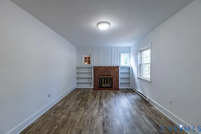 a view of an empty room with a window and wooden floor